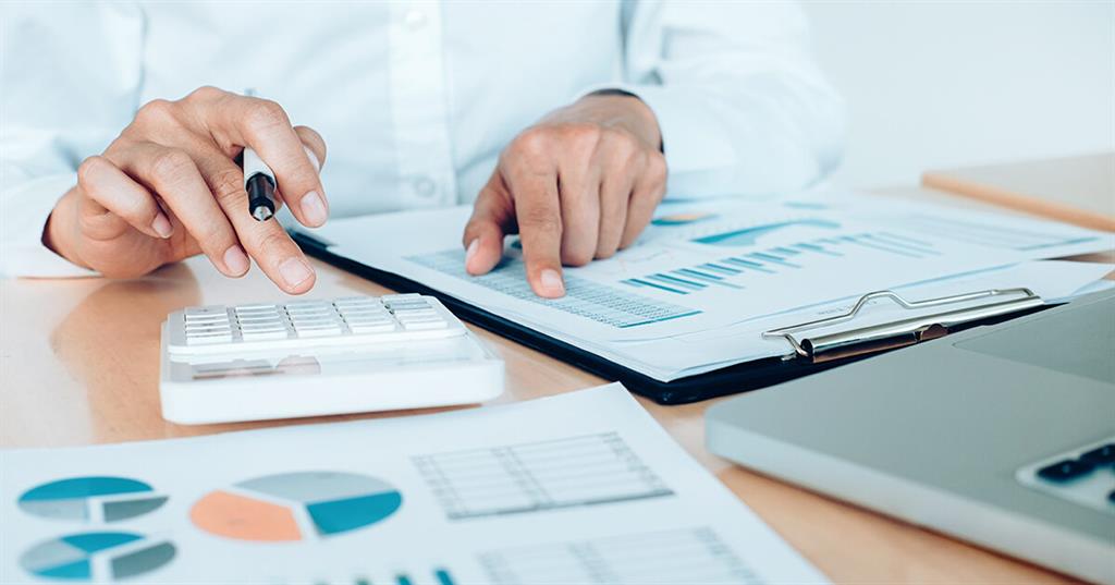 Acheteur immobilier qui analyse son budget avec une calculatrice, un ordinateur et des documents de prêt